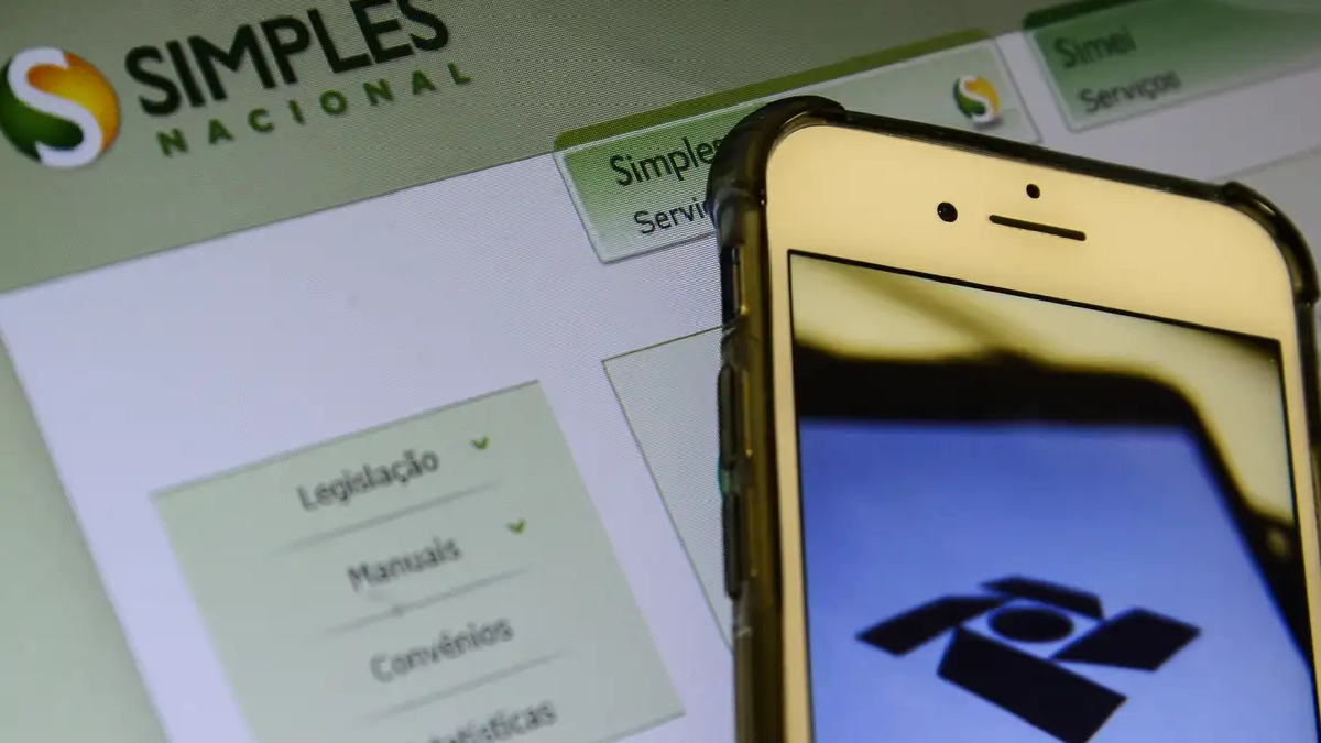 Celular e tela com logo do Simples Nacional. Foto: Marcello Casal Jr./Agência Brasil